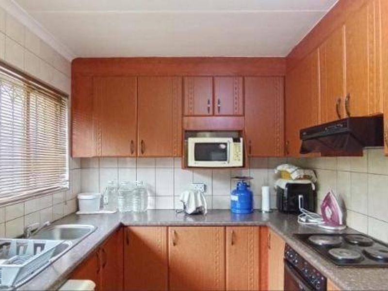 A functional kitchen featuring wood-look cabinetry, laminate countertops, a built-in oven with hob, and a tiled backsplash.