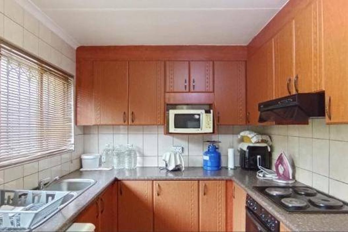 A functional kitchen featuring wood-look cabinetry, laminate countertops, a built-in oven with hob, and a tiled backsplash.