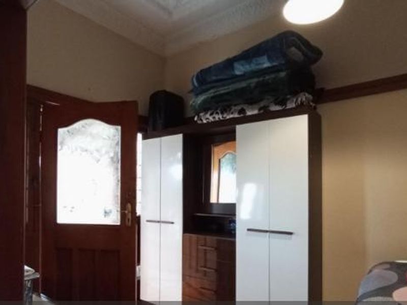 A bedroom featuring a built-in wardrobe with white doors and decorative ceiling cornicing.