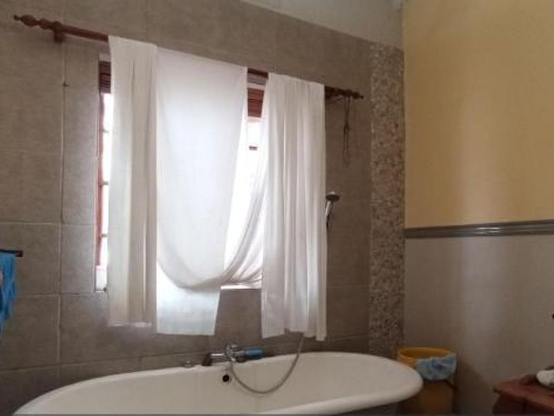 A bathroom featuring a freestanding bathtub, tiled wall accents, a vessel sink with a mirror, and functional towel storage.
