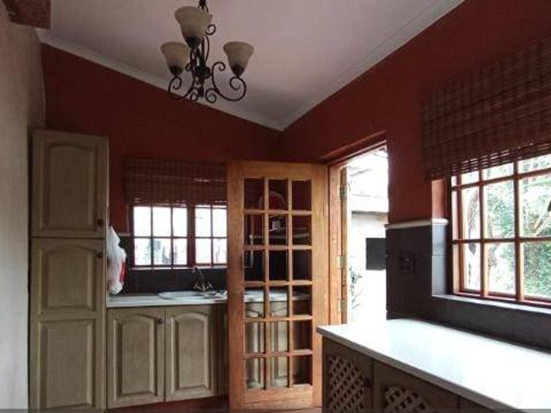 A functional kitchen featuring built-in cabinetry, tiled splashbacks, and timber-framed windows, offering a classic aesthetic with potential for modern updates.