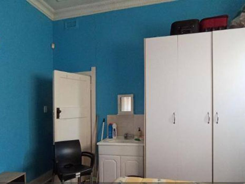 Bedroom featuring a built-in wardrobe and a small vanity basin area with blue painted walls and decorative cornice detail.