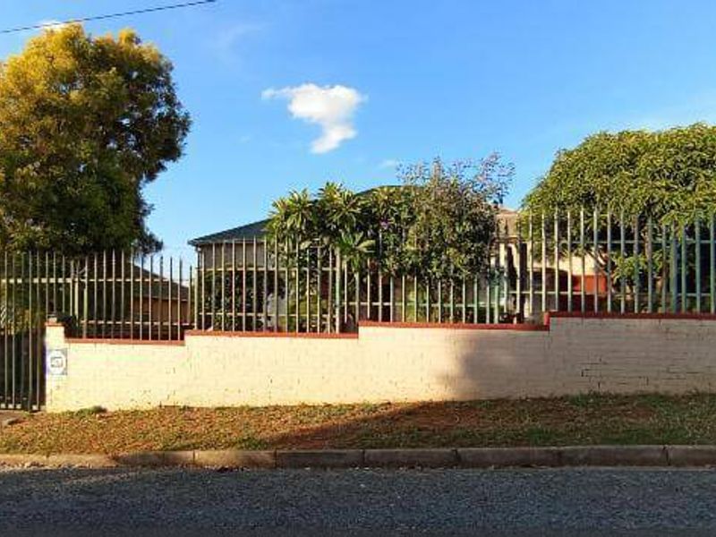 Front elevation of the property featuring a secure perimeter wall with steel palisade fencing and gated access.