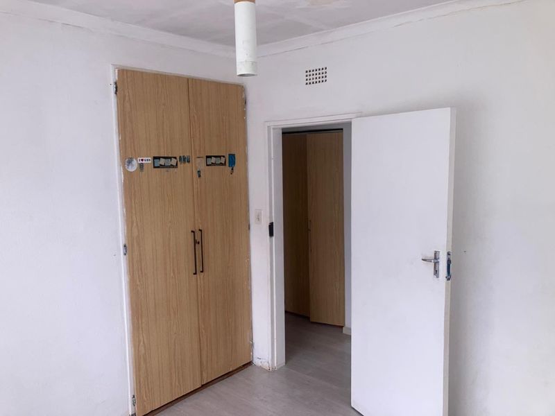 A vacant bedroom featuring built-in wooden cupboards and a neutral interior, offering a blank canvas for potential updates and personalization.