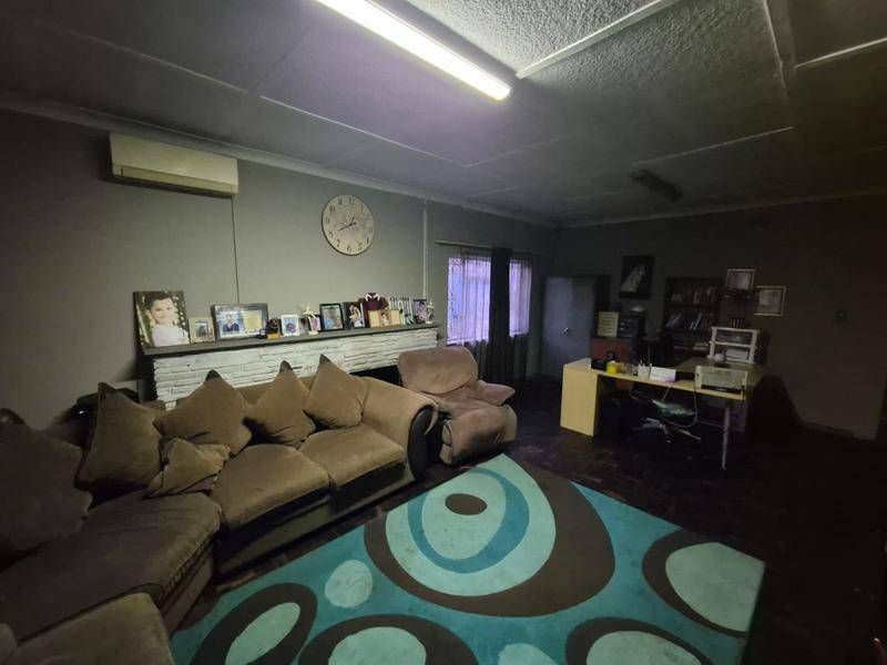 A living room featuring a stone-clad fireplace, split-system air conditioning, and fluorescent lighting, requiring cosmetic updates to improve the overall aesthetic.