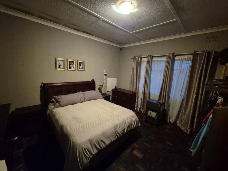 A bedroom featuring dark parquet flooring and a tiled ceiling, offering a functional space with potential for cosmetic updates.