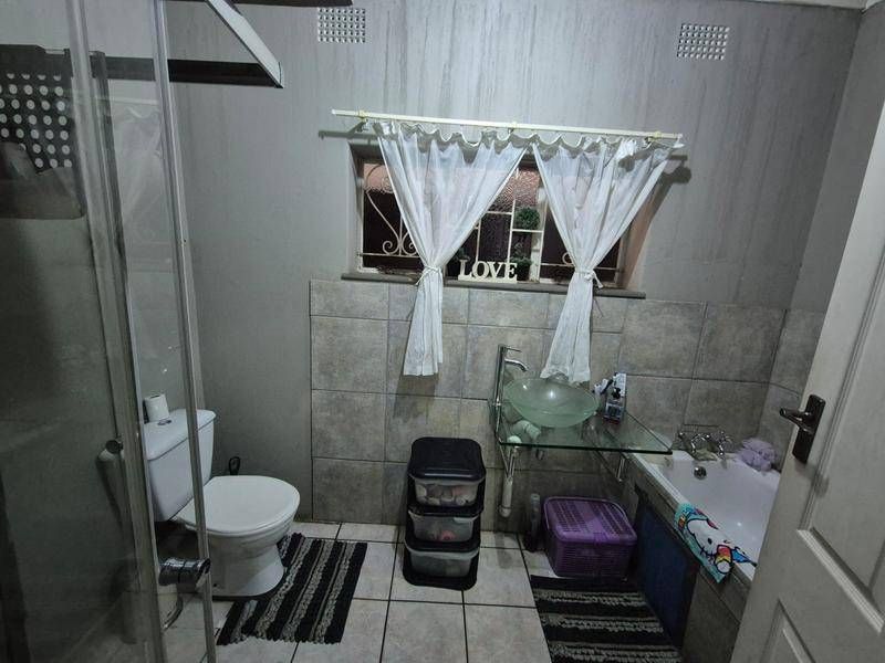Compact bathroom featuring a glass vessel sink, built-in bathtub, and a separate glass-enclosed shower area with tiled finishes.
