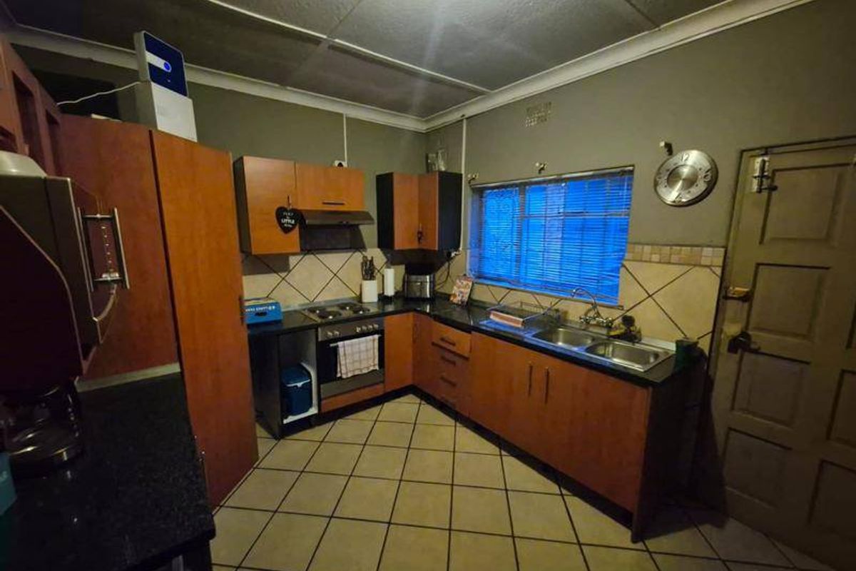 A functional kitchen featuring wood-tone cabinetry, dark countertops, a built-in oven with hob, and tiled flooring, offering a practical layout for daily use.