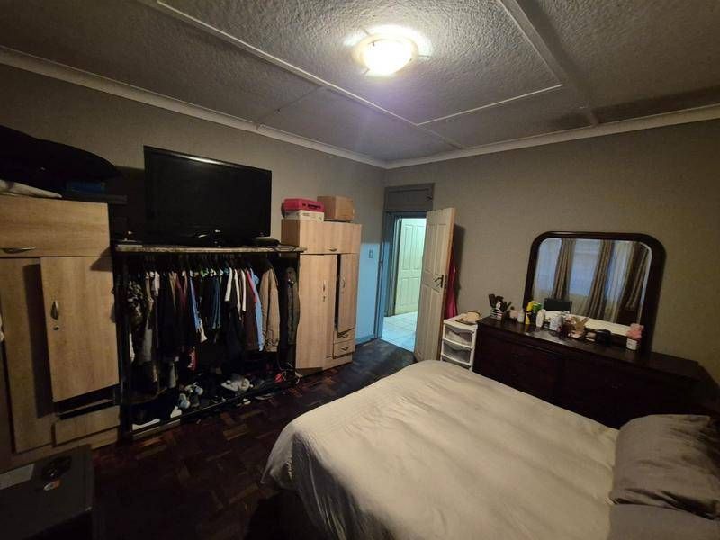 A bedroom featuring parquet flooring and a coved ceiling, offering a functional space with potential for cosmetic updates.