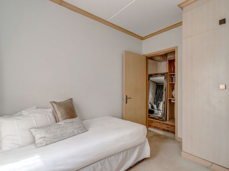 A bedroom featuring built-in light wood cabinetry and crown molding, with an adjoining doorway leading to a secondary space.