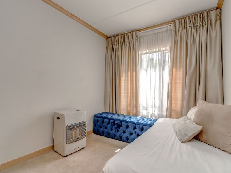 A bedroom featuring neutral carpeting, crown molding, and floor-to-ceiling curtains covering the window.