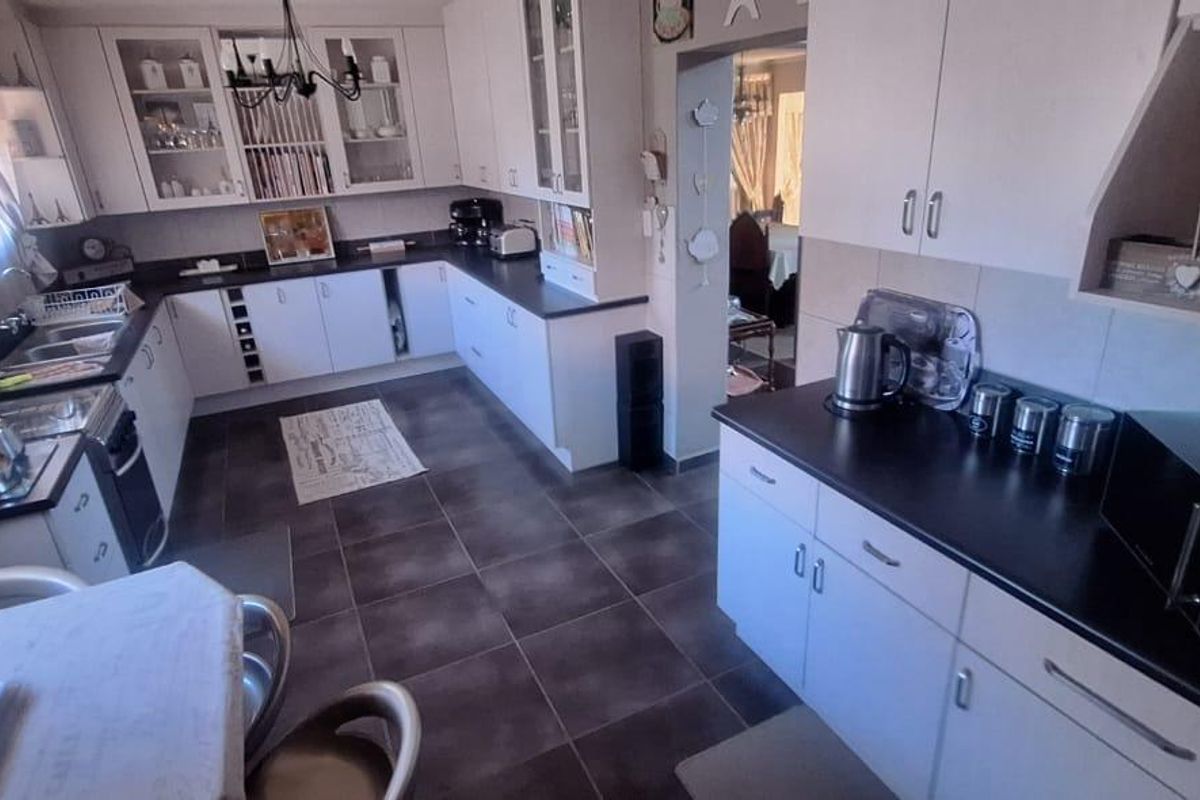 A functional kitchen featuring white cabinetry, dark countertops, tiled flooring, and a built-in oven, offering a clean and practical workspace.