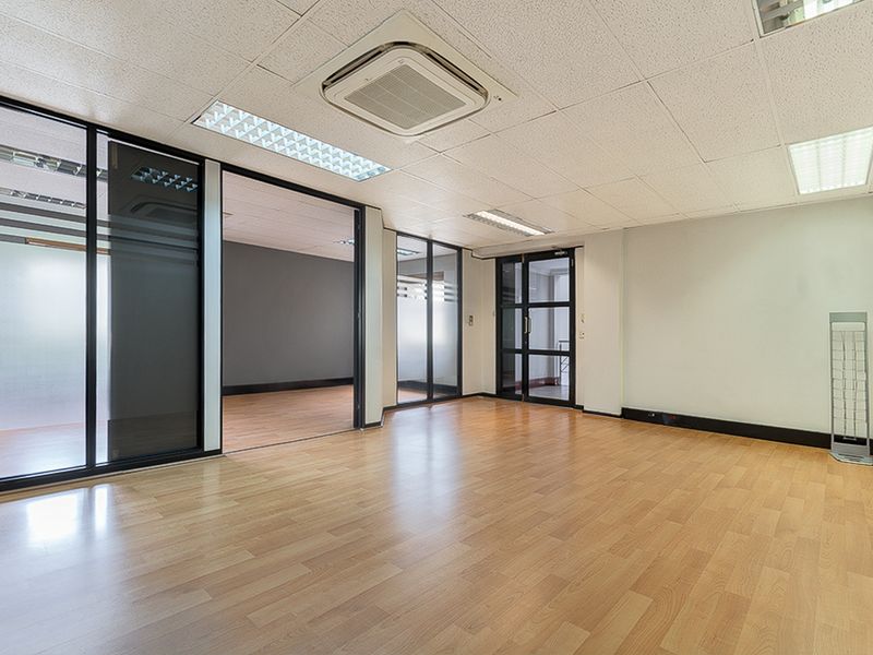 Spacious commercial office area featuring laminate flooring, suspended ceilings with integrated lighting, and modern glass partition walls for a professional, open-plan workspace.
