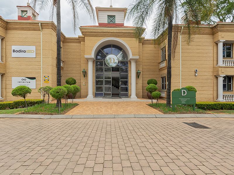 Front elevation of a commercial office building featuring a paved driveway, arched entrance, and classic architectural detailing.