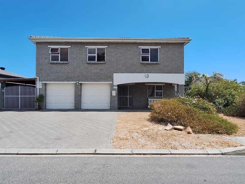 A two-story brick house featuring a double garage, paved driveway, and a covered entrance, set within a low-maintenance landscaped front yard.