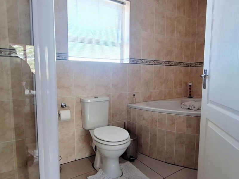 A functional bathroom featuring a built-in bathtub, separate shower enclosure, and neutral ceramic tiling throughout.