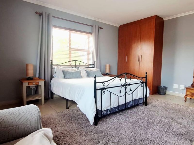 A well-maintained bedroom featuring built-in wooden cupboards, neutral wall tones, and tiled flooring, offering a comfortable and functional living space.