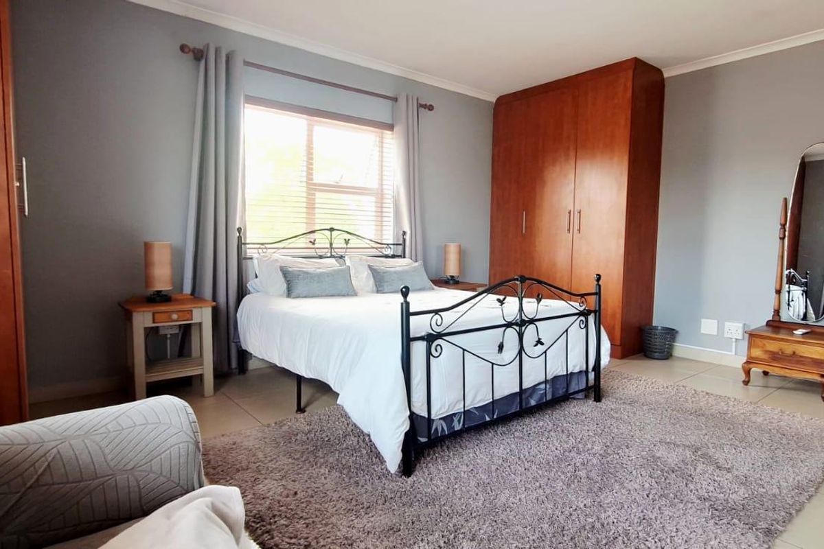 A well-maintained bedroom featuring built-in wooden cupboards, neutral wall tones, and tiled flooring, offering a comfortable and functional living space.