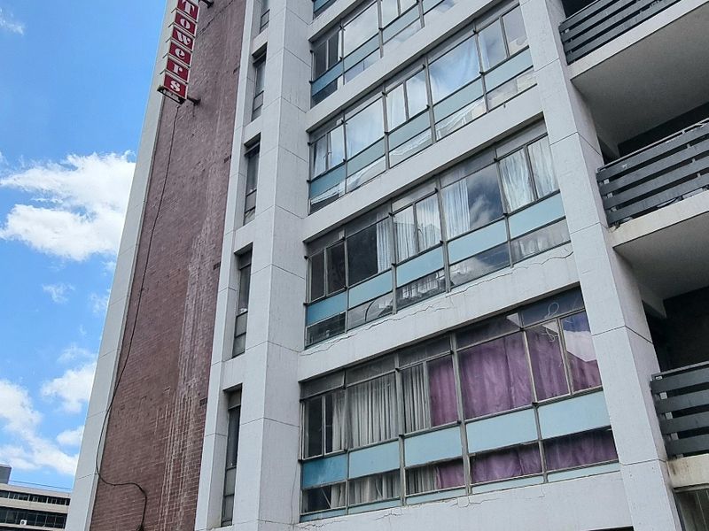 A low-angle view of a multi-story apartment building facade featuring stacked balconies and large window panels with visible signs of exterior weathering.