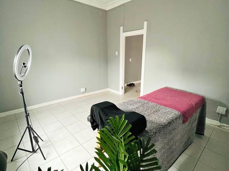 A bedroom featuring tiled flooring, decorative ceiling molding, and a ceiling fan, currently utilized as a treatment room.