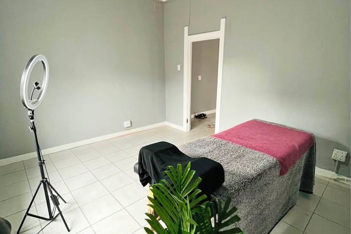 A bedroom featuring tiled flooring, decorative ceiling molding, and a ceiling fan, currently utilized as a treatment room.
