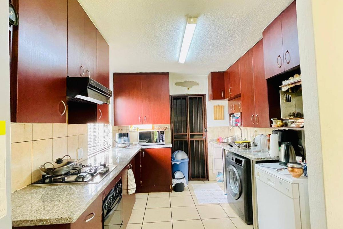 Functional kitchen featuring dark wood cabinetry, granite countertops, gas hob, and tiled flooring, with direct access to the rear of the property.