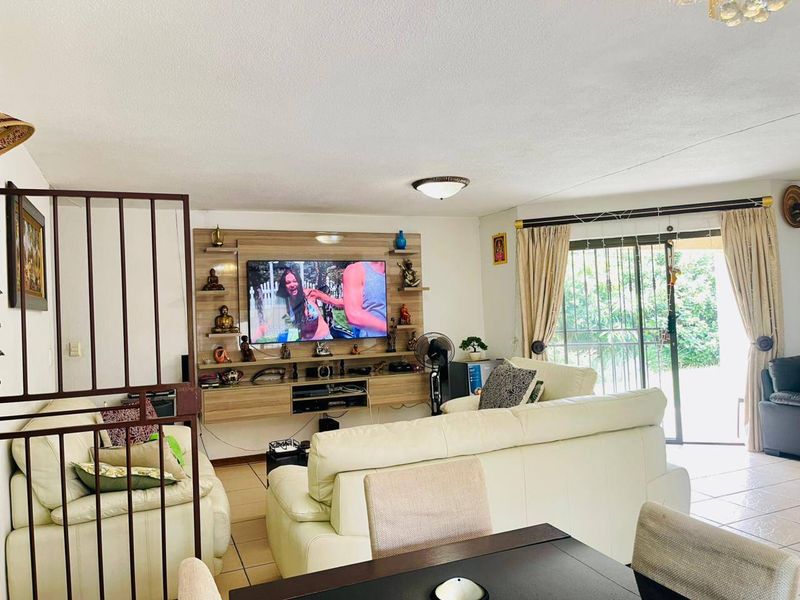 Spacious living room featuring a built-in media unit, tiled flooring, and large sliding glass doors providing access to the outdoor area.