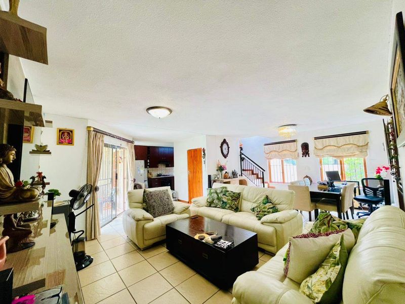 Spacious open-plan living and dining area featuring tiled flooring, a staircase with metal railing, and direct access to the outdoor space via sliding doors.