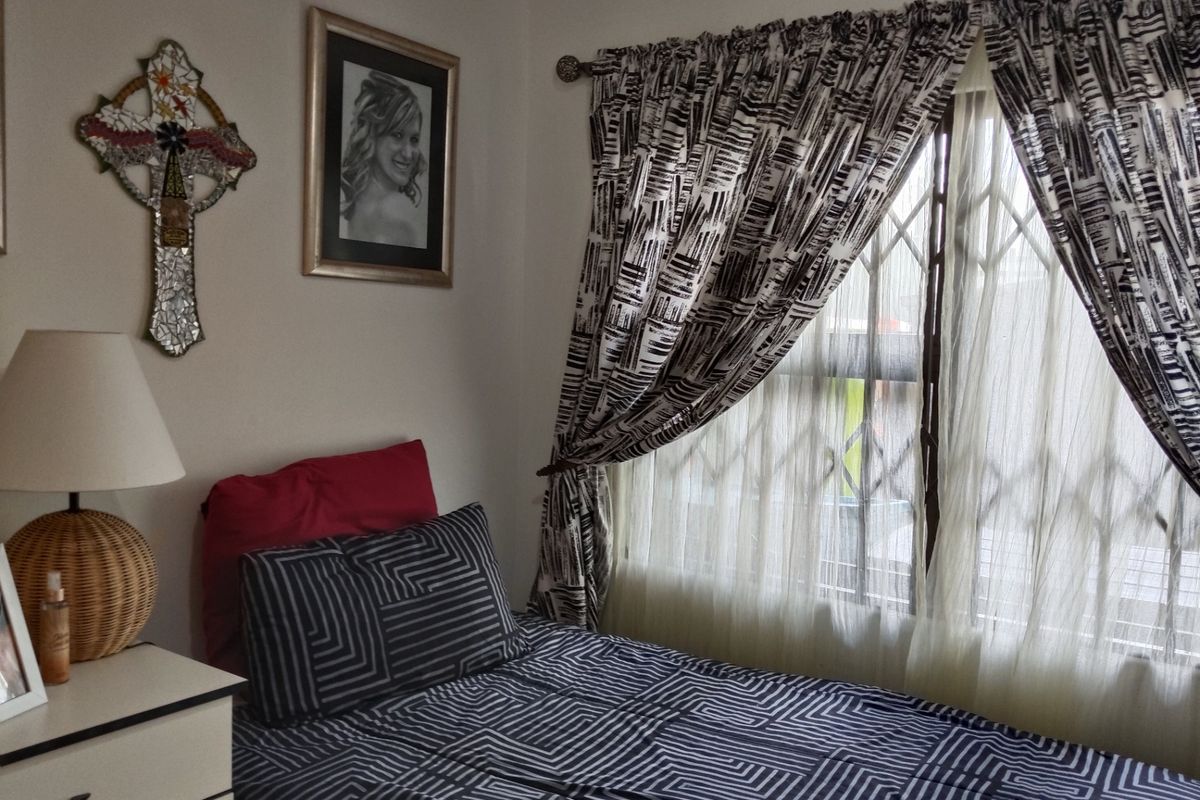 A cozy bedroom featuring a window with a fitted security gate and curtain rod, providing natural light and essential security.