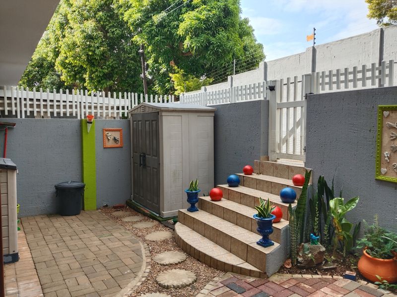 A private rear courtyard featuring paved flooring, tiled steps leading to a pedestrian gate, and secure boundary walls with electric fencing.