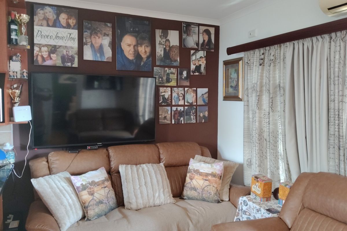 A cozy living room featuring a dark accent wall, air conditioning unit, and window treatments.