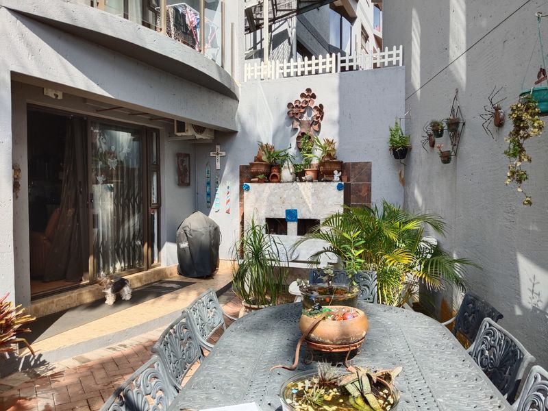 A private paved patio area featuring a built-in braai and direct access to the interior through sliding glass doors.