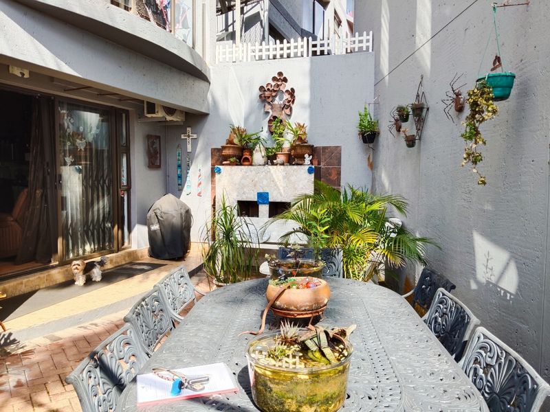 A private outdoor patio area featuring a built-in fireplace, paved flooring, and direct access to the interior through sliding glass doors.
