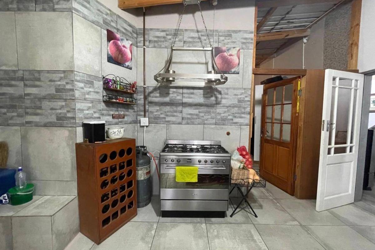 Kitchen area featuring a gas stove with overhead extractor fan, tiled splashback, and exposed timber ceiling beams.