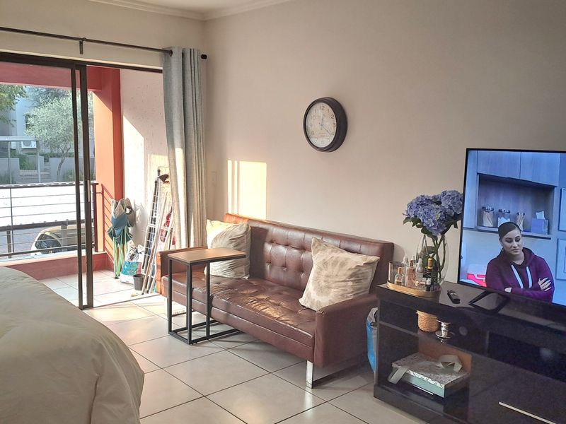 A well-lit bedroom featuring tiled flooring and a sliding glass door providing direct access to a private balcony.