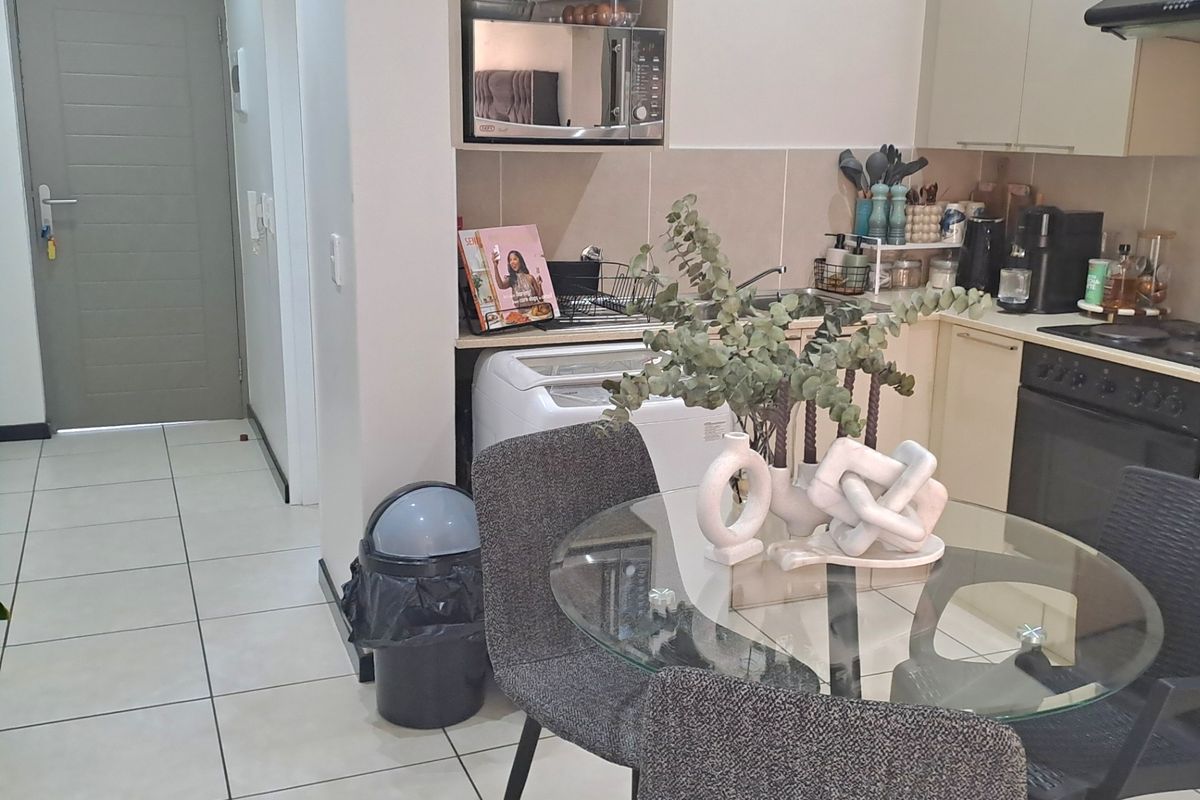 A functional kitchen featuring built-in cabinetry, integrated oven and hob, extractor fan, and tiled flooring, providing a practical cooking and dining space.