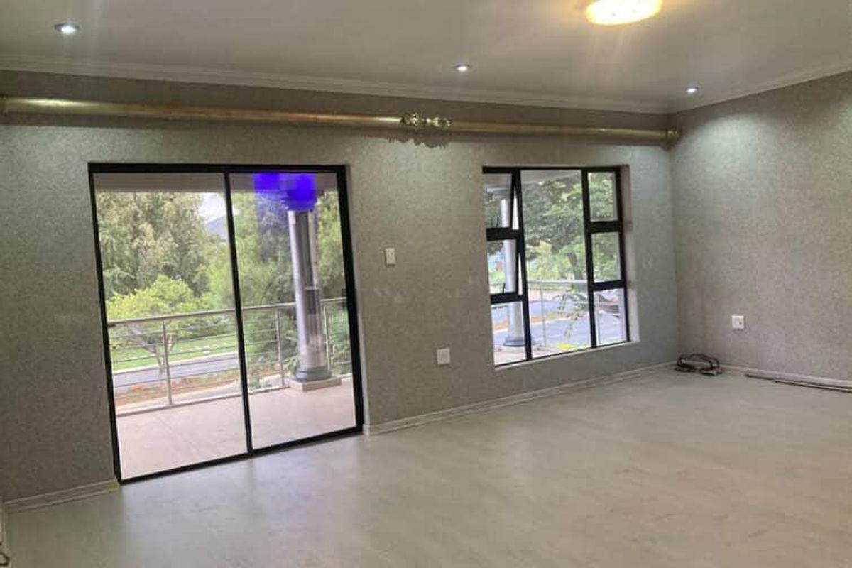 Spacious, empty living area featuring modern laminate flooring, textured wallpaper, recessed lighting, and large sliding doors leading to an outdoor balcony.