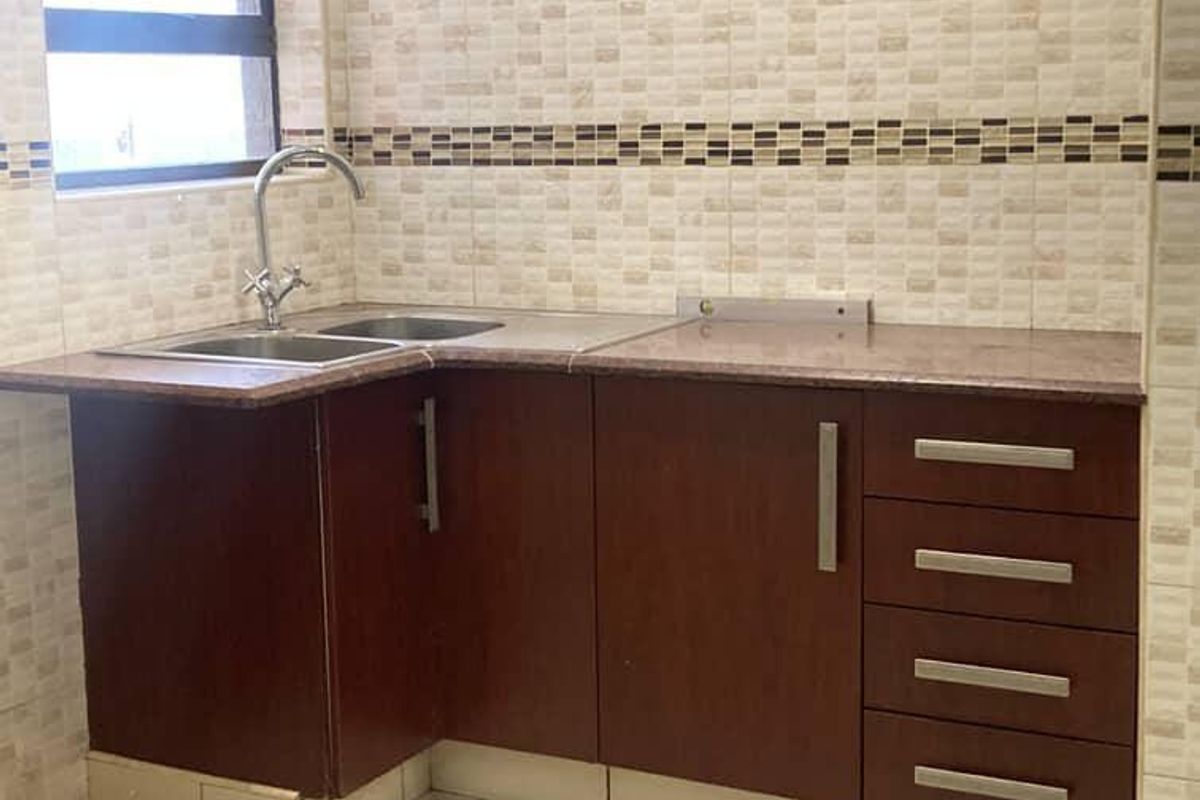 A functional kitchen corner featuring dark wood-look cabinetry, granite countertops, a double stainless steel sink, and a tiled backsplash.