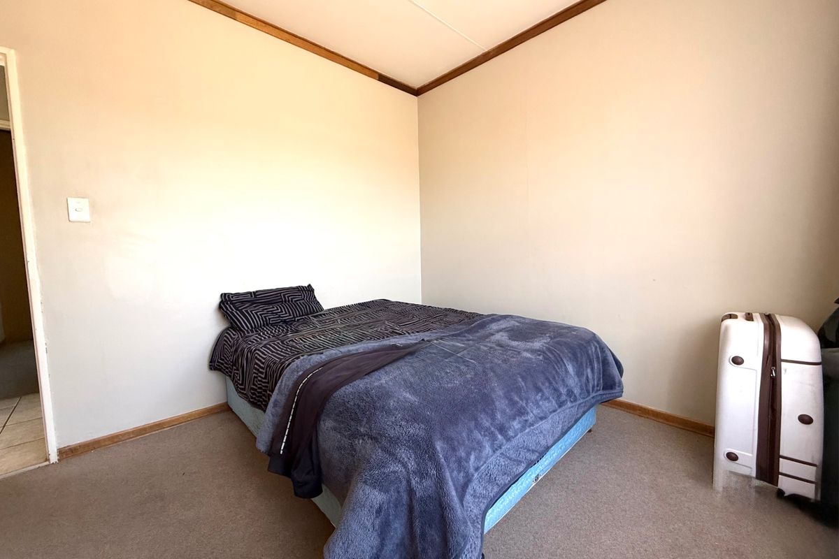A simple bedroom featuring neutral walls, timber trim details, and carpeted flooring, offering a blank canvas for potential updates.