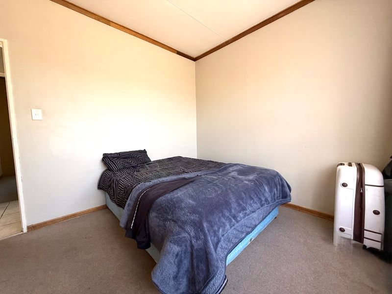 A simple bedroom featuring neutral walls, timber trim details, and carpeted flooring, offering a blank canvas for potential updates.