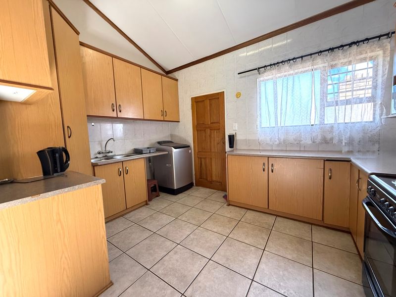 A functional kitchen featuring light wood-look cabinetry, tiled flooring, a tiled backsplash, and integrated oven, offering a practical layout for daily use.