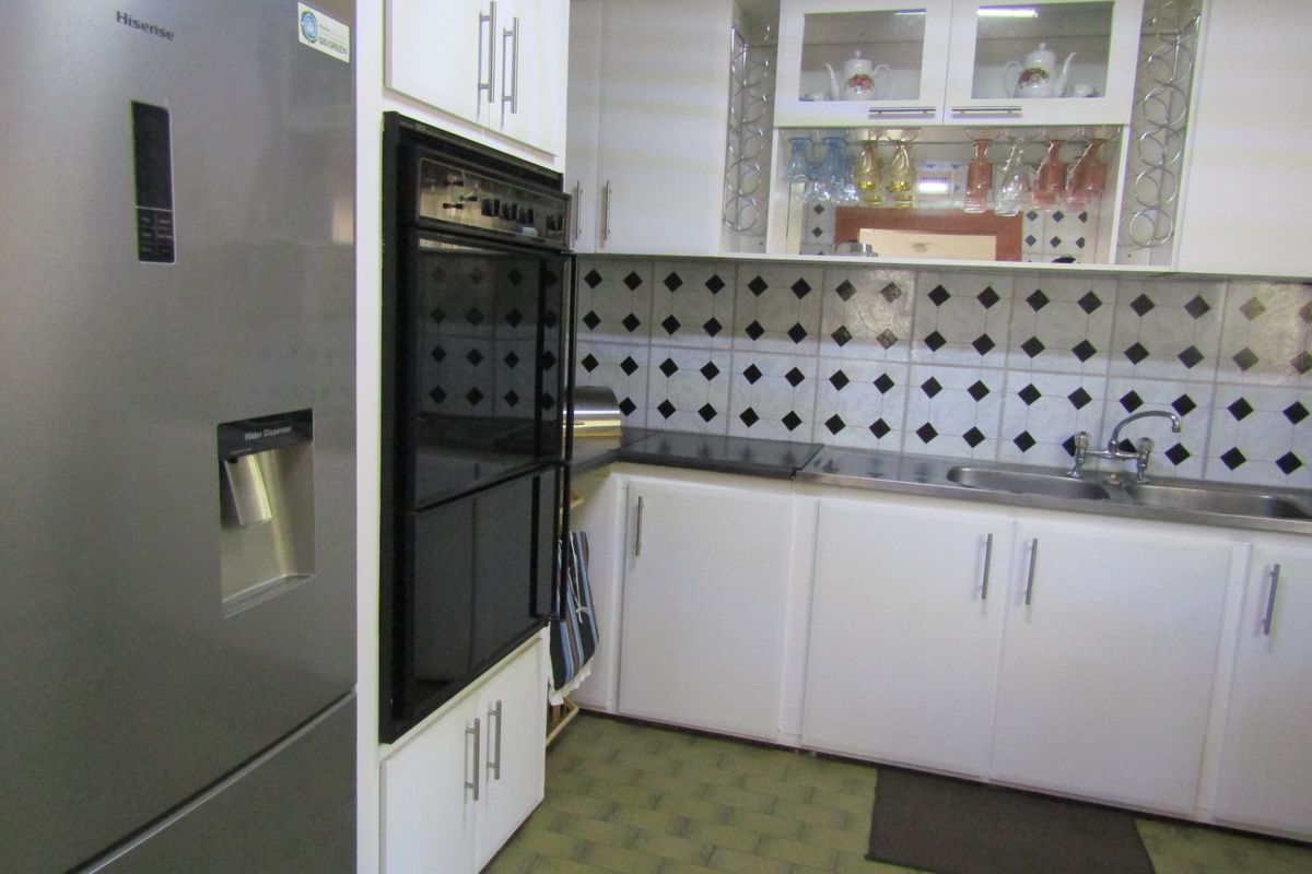 A functional kitchen featuring white cabinetry, a built-in oven, a double sink, and a decorative tiled backsplash.