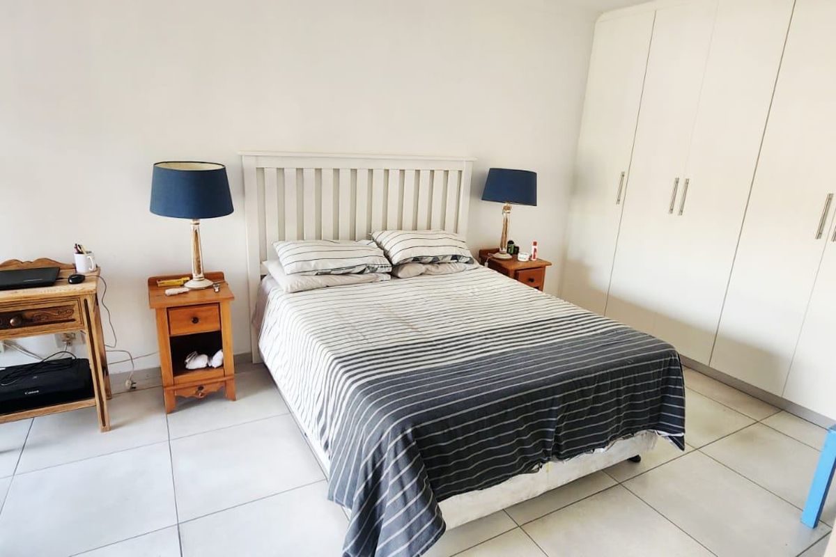 A functional bedroom featuring neutral tiled flooring and ample built-in cupboard storage space.