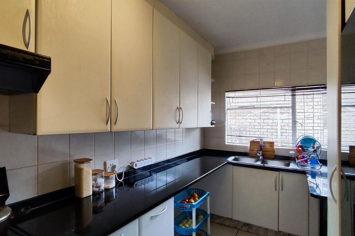 Functional kitchen featuring dark granite countertops, ample cabinetry, a stainless steel double sink, and a tiled backsplash.