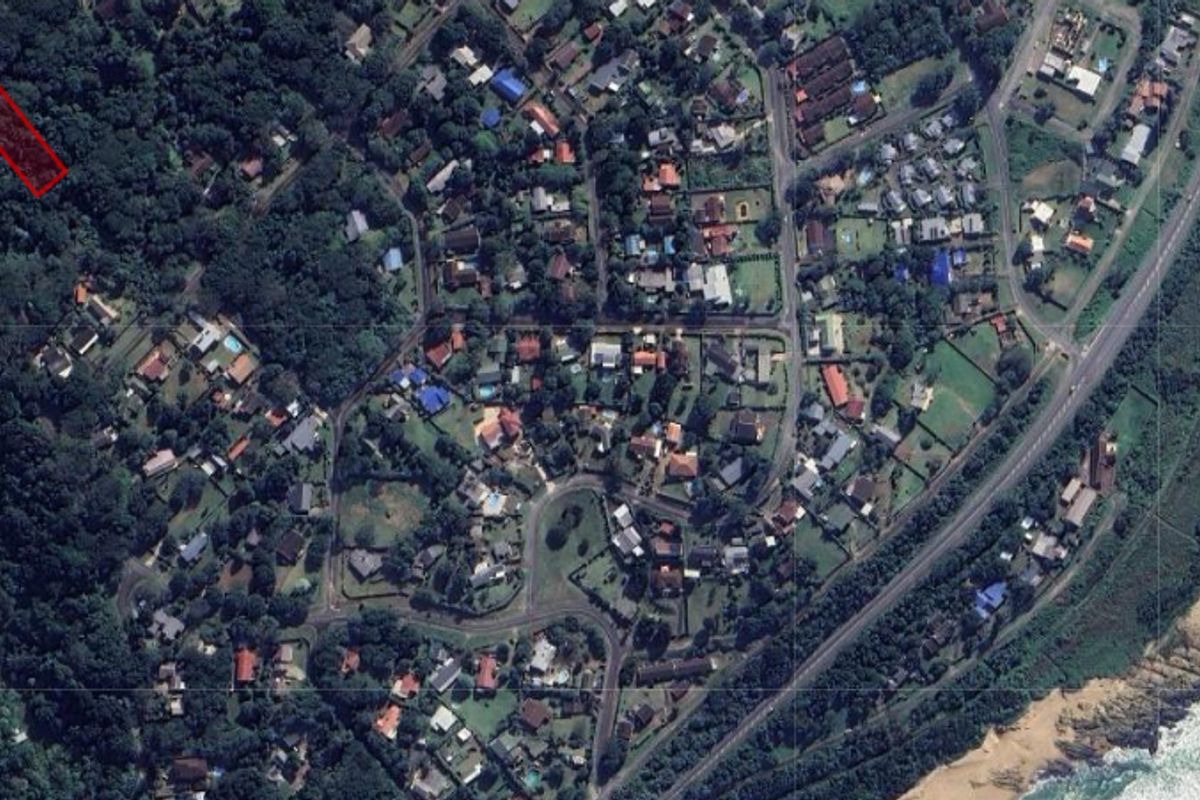 Aerial view of a residential vacant land plot highlighted in red, situated within a established coastal neighborhood.