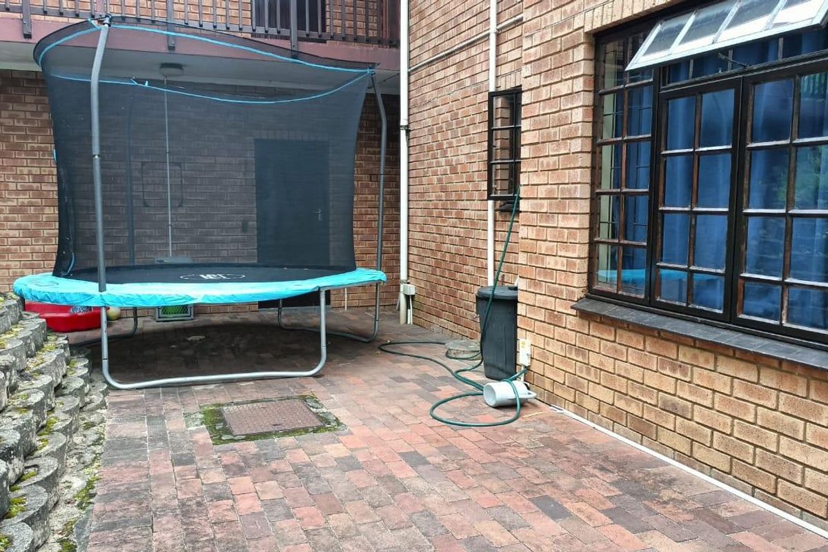 A rear exterior area featuring brick paving, a face brick facade, and a tiered retaining wall structure.