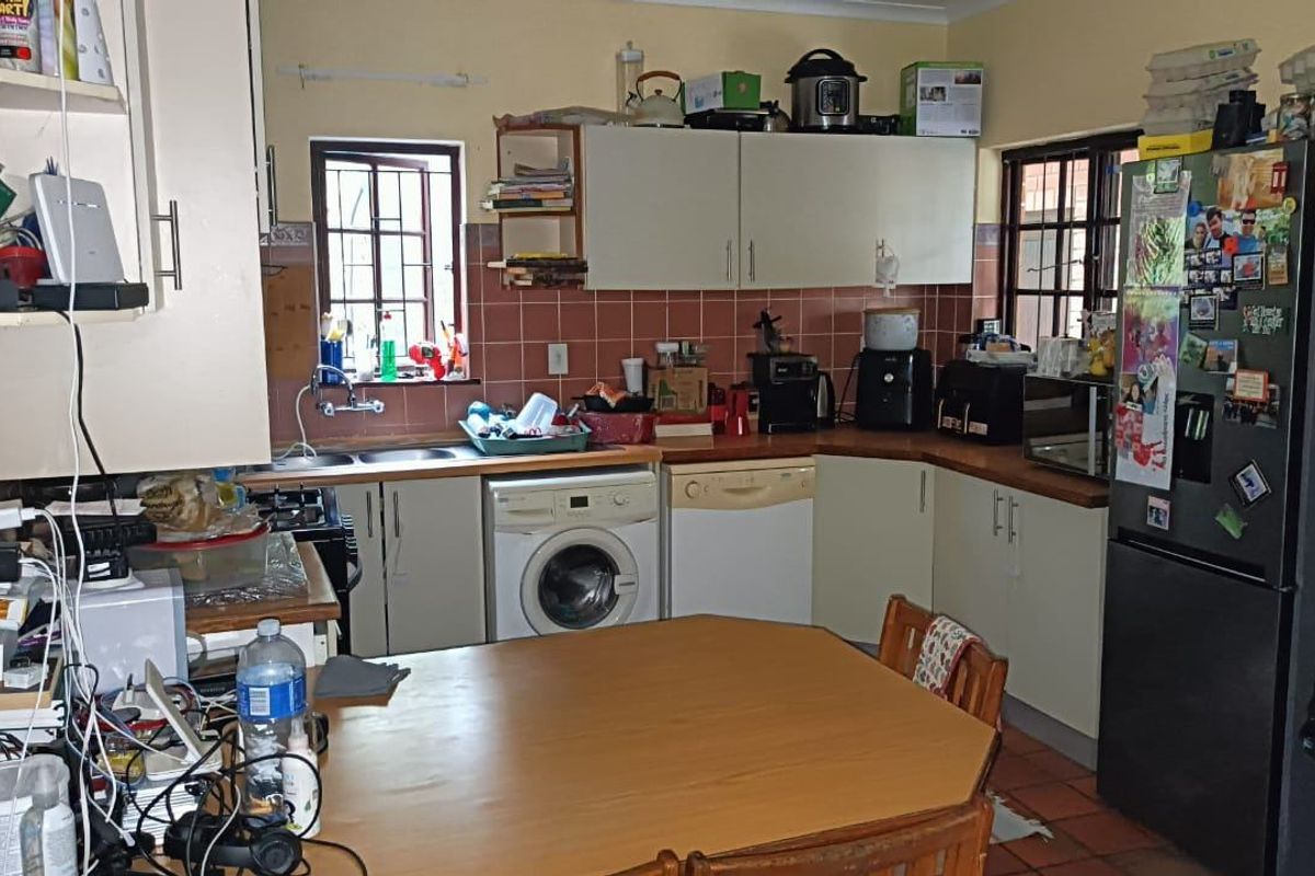 A functional kitchen featuring built-in cabinetry, tiled backsplash, and integrated laundry and dishwasher appliances, offering potential for modernization and improved layout efficiency.