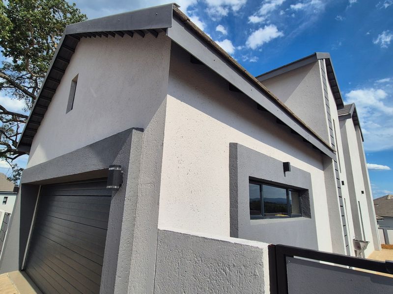 A modern residential exterior featuring a clean textured plaster facade, a secure garage door, and contemporary architectural detailing.