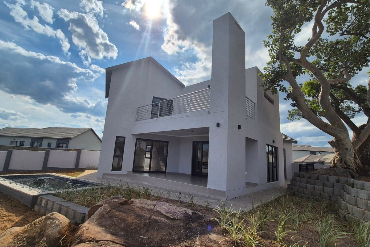 Rear view of a modern two-story house featuring a covered patio, upper balcony with stainless steel balustrade, and a private swimming pool.