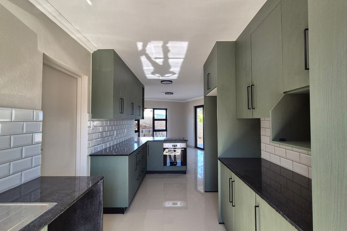 Modern kitchen featuring sage green cabinetry, dark stone countertops, white subway tile backsplash, and integrated appliances with polished floor tiles.